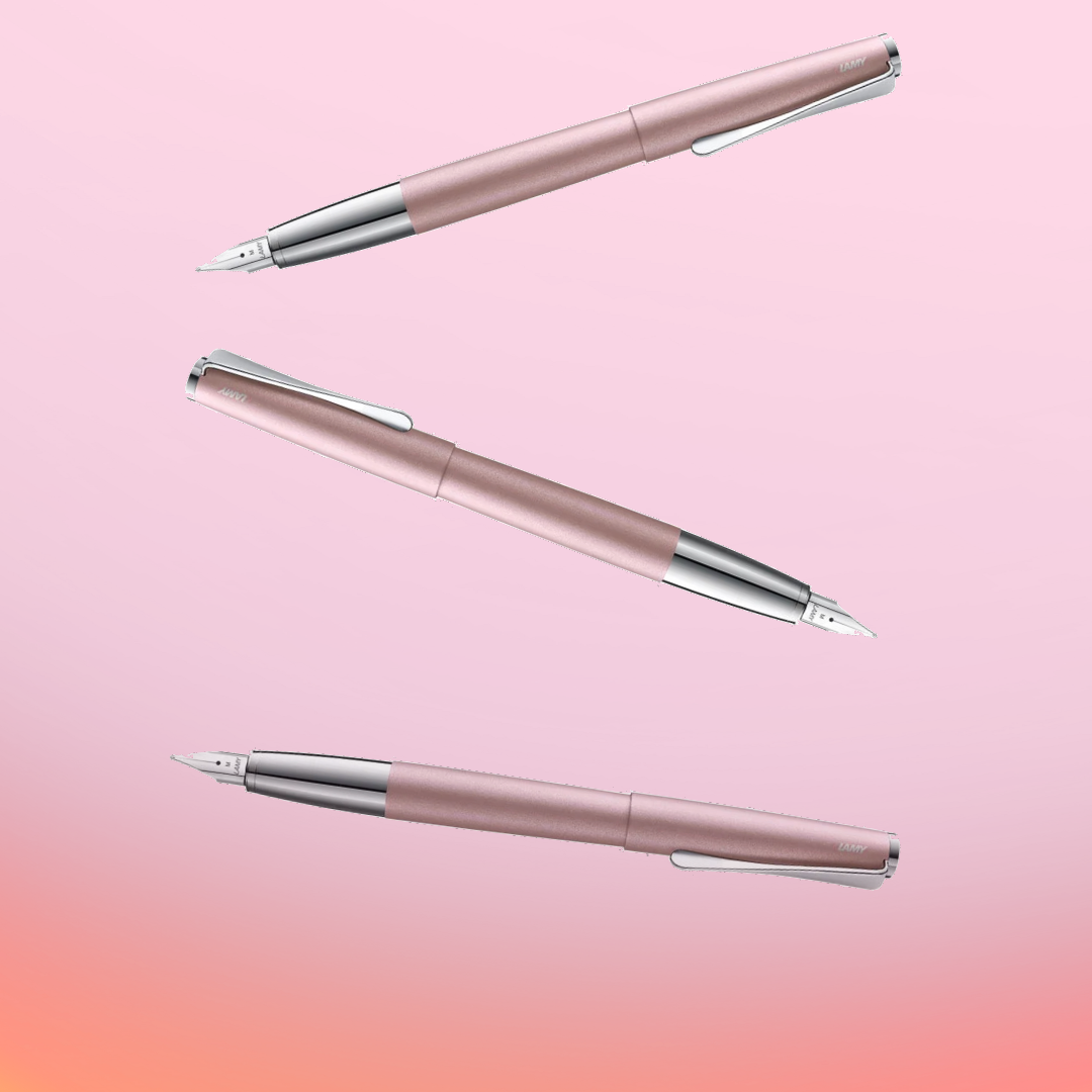 Pink Lamy 2000 fountain pens floating in the air against a pink gradient background.