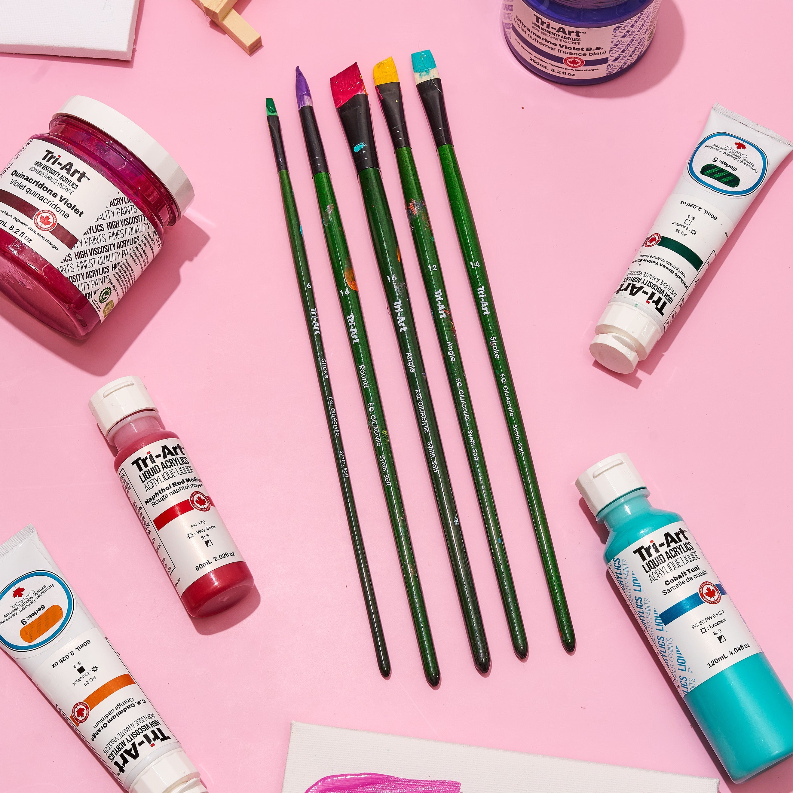 A flat lay image of artist heavy body, liquid acrylic paints and brushes. 