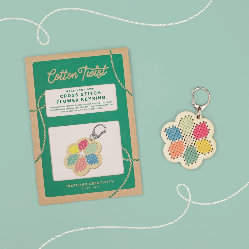 Wooden flower cross stitch keyring kit with pastel threads and embroidery needle on white background